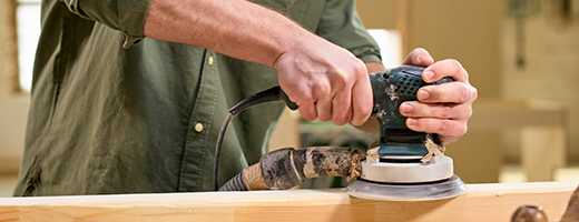 Image of male hands using an electric sanding tool