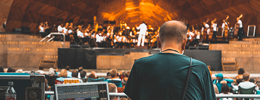 Image of senior man working the sound booth at an orchestra concert