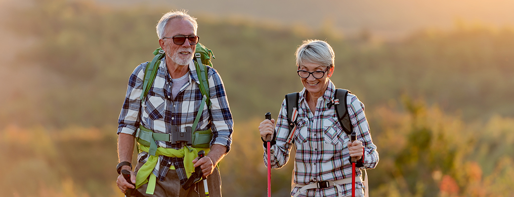 Senior man and senior woman hiking with walking sticks