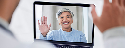 Image of laptop screen showing hearing care professional waving to the patient who is looking at the laptop