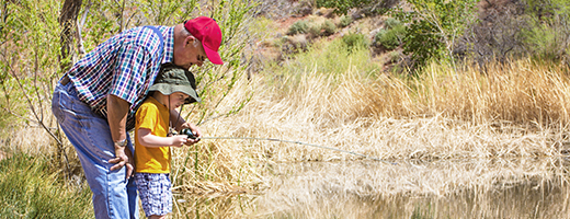 Image of senior man helping his grandson fly-fish