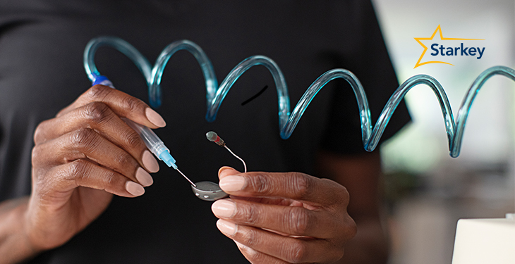 Image of a hearing professional cleaning a hearing aid