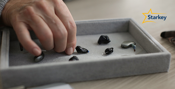 Image of hand choosing a hearing aid from an assortment